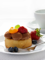 Fresh fruit tart with fork and coffee cup on background