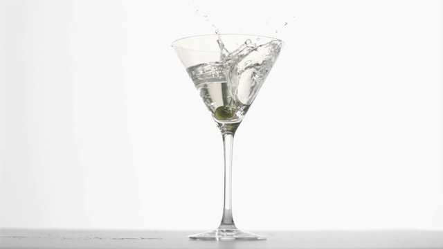 Olive diving in super slow motion in a martini