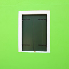 detail of vivid green facade with window with closed shutters, B