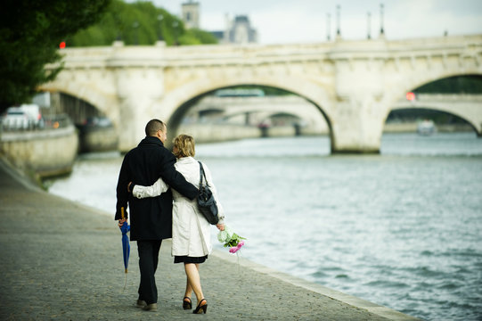 Caucasian couple hugging and walking near city river
