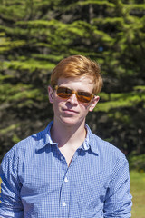 teenage boy with sunglasses walks happy on the meadow