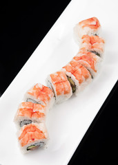 japanese sushi rolls on a white plate over black background