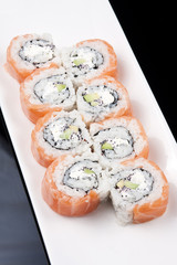 japanese sushi rolls on a white plate over black background