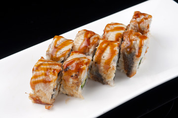 sushi roll on white plate over black background