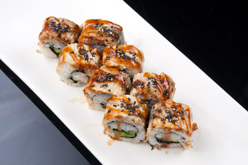 japanese sushi roll on white plate over black background