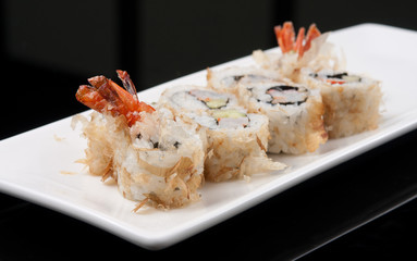 japanese sushi roll on white plate over black background