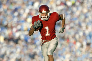 African American football player running on field in game