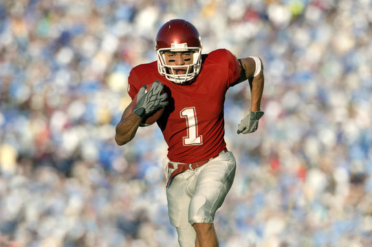 African American football player running on field in game - Powered by Adobe