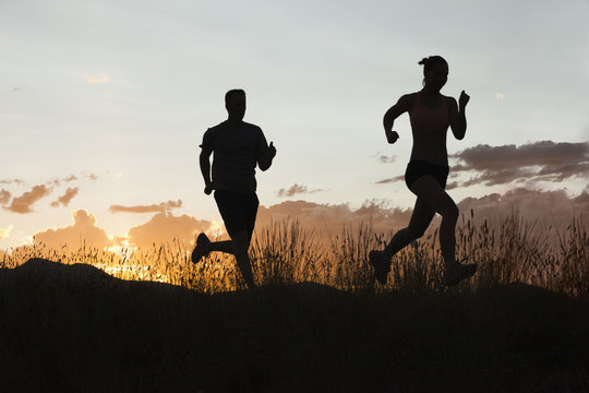 Caucasian couple running together at sunset