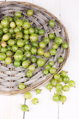 Green gooseberry on wicker mat on wooden background