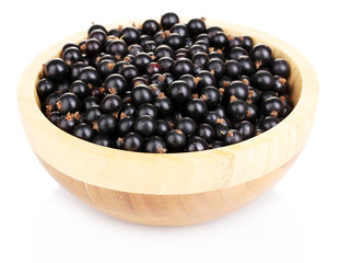 Black currant in wooden bowl isolated on white
