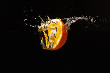 Halved fresh orange falling into the water with a splash
