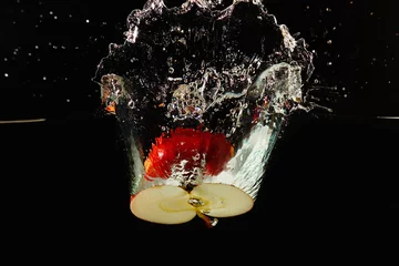  Gehalveerde rijpe appel die met een plons in het water valt © Boris Bulychev