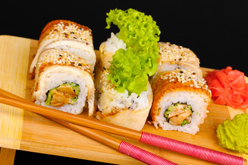 Tasty rolls served on wooden plate isolated on black