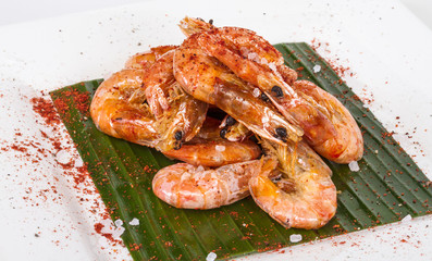 fried black tiger prawns with herbs and spices on banana leaf