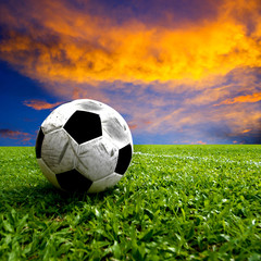 Football, real soccer ball on green grass at sunset