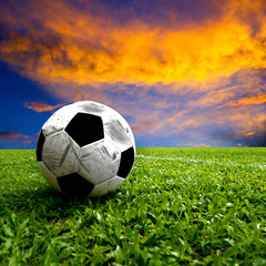 Fototapeta premium Football, real soccer ball on green grass at sunset