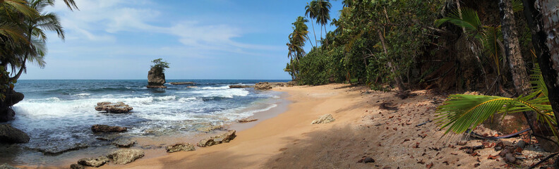 Panorama on a beautiful sandy beach with rocky islet and tropical vegetation, Caribbean sea, Costa Rica, Central America