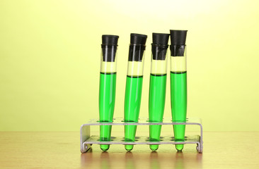 Test-tubes with green liquid on wooden table on green