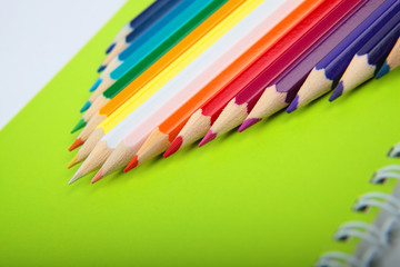 Bright multicolor pencils on green notebook