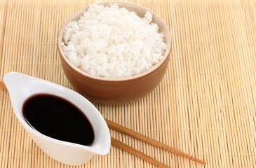 Bowl of rice and chopsticks on bamboo mat