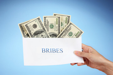 Woman's hand holding an envelope with money on blue background