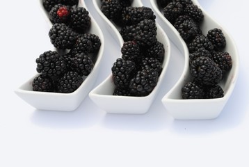 juicy blackberries into shaped dishes, on white background