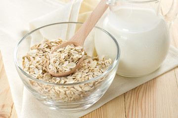 Oat flakes on a glass boel and jug of milk