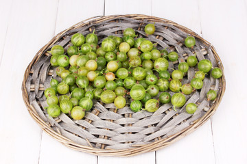 Green gooseberry on wicker mat on wooden background