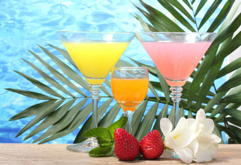exotic cocktails and flowers on table on blue sea background