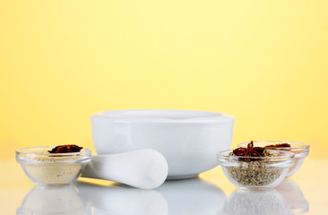 White mortar and pestle with spice on yellow background