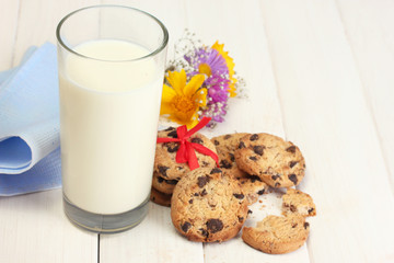glass of milk, chocolate chips cookies with red ribbon and