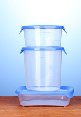 Plastic containers for food on wooden table on blue background