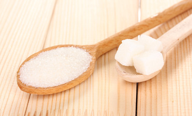 White sugar in spoons on wooden background