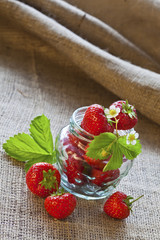 Red strawberries in glass jar on sackcloth