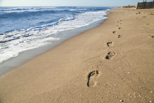 Orme di un uomo che passeggia sulla spiaggia in riva al mare