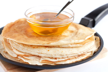 Round pancakes in a frying pan and honey