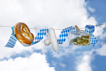 Okoberfest, Volksfest, fair, Bier, Breze und Weisswürste hängen an Schnur vor weiß-blauem...