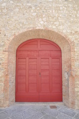 Fototapeta na wymiar Wooden gate and a stone wall, characteristic buildings Tuscany