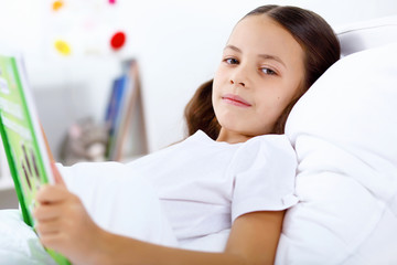 Girl with a book in bed at home