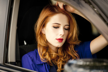 Naklejka na ściany i meble Beautiful redhead woman in the car.