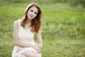 Fototapeta na wymiar Redhead girl at green grass at village outdoor.