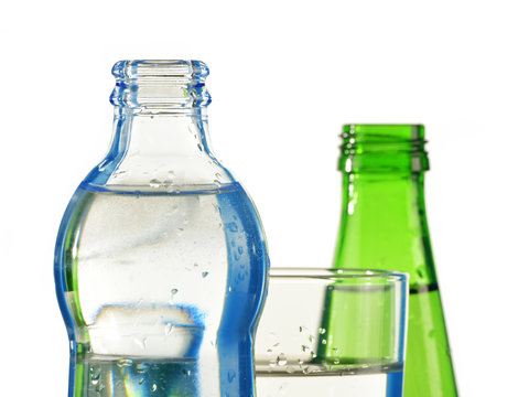 Two bottles of mineral water and glass isolated on white