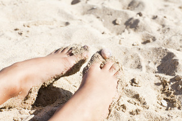 thins legs in the sand with cockleshells