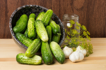 Bowl of pickles with jar and garlic