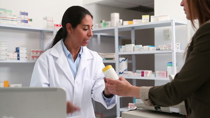 Smiling female pharmacist handing drugs to a customer - Powered by Adobe