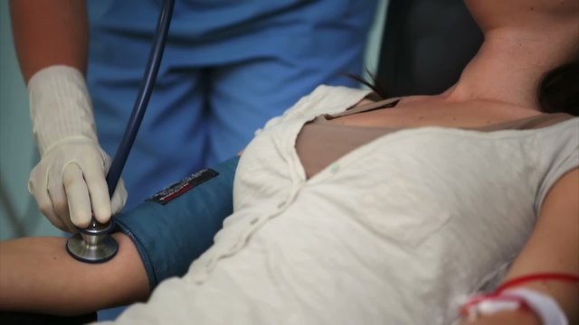 Nurse checking pulse of a donor with a stethoscope