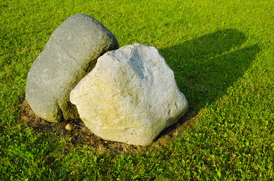 Two big stones in meadow surrounded with cut grass