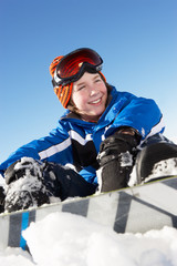 Fototapeta na wymiar Chłopiec Siedzi Na śniegu z snowboard