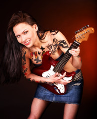 Obraz premium Aggressive girl with tattoo playing guitar.